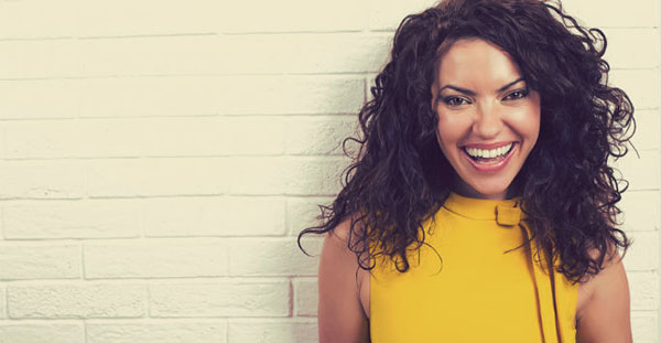 Woman smiling, standing in front of brick wall