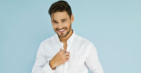 Man in white, posing and smiling