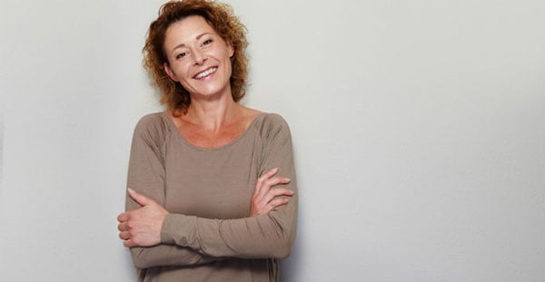 Older woman smiling, on gray background