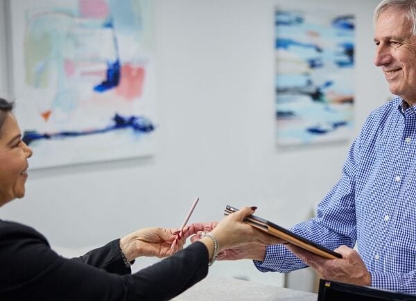 Staff Member Handing Tablet to Patient