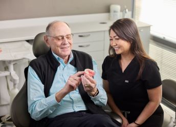 Dental patient examining a prosthetic while consulting a CascadesONE professional